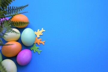 Colorful Easter eggs. Banner, wallpaper, postcard, social media post with copy space for text. Painted eggs arranged on one side on a blue background