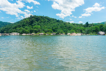 Tranquil natural scene with blue mountains, blue sky, and scattered rocks on the rippling river. Eco-tourism on a sunny day	