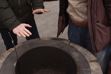Fototapeta na wymiar people warming hands around fireplace at cold winter season. Urban street outdoor