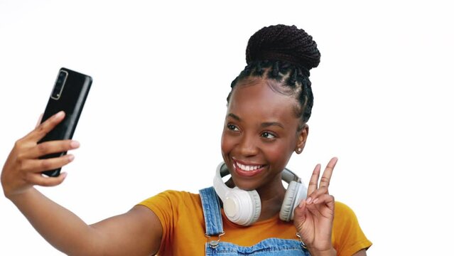 Black woman, studio selfie and phone with peace, smile or headphones by white background for fashion. Gen z student girl, smartphone and influencer with isolated profile picture on social network app