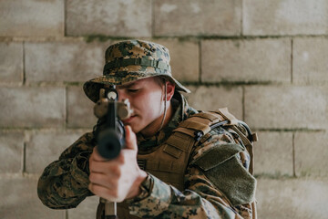 Fototapeta premium A soldier in uniform stands in front of a stone wall in full war gear preparing for battle