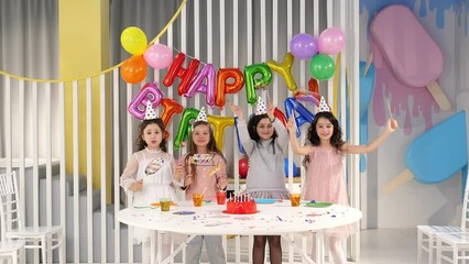 Funny girls dance at a birthday party with paper accessories, pipe caps. Children's birthday party. Childhood, holidays, friendship concept.