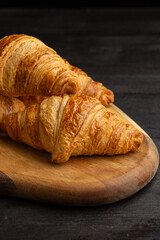 Top view of croissants on board on dark wooden table, vertical, with copy space