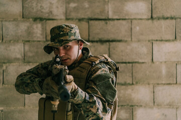 A soldier in uniform stands in front of a stone wall in full war gear preparing for battle