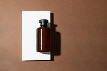 Abstract cosmetic bottle with shampoo, gel or lotion product on the white podium on brown background.Top view , copy space