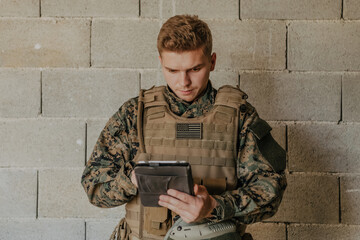 Soldier using tablet computer against old brick wall