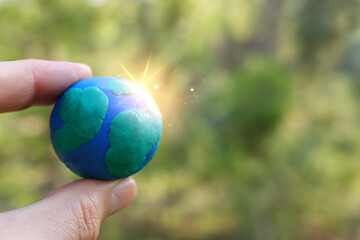Fototapeta Model of earth on the ground in the forest with bright sun light. Sustainability and ecology concept obraz