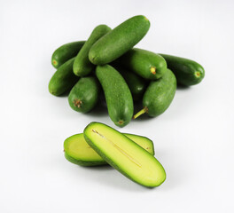 Cut and whole seedless mini avocados isolated on white. A group of mini avocado or cocktail avocado stacked to pyramid on white background. Green vegan functional food for healthy lifestyle, superfood
