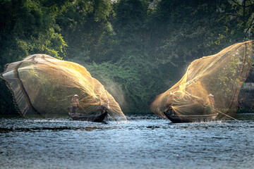 Scene of Vietnamese fishermen casting their fishing nets on a boat in the peaceful Nhu Y river in Hue, Vietnam
