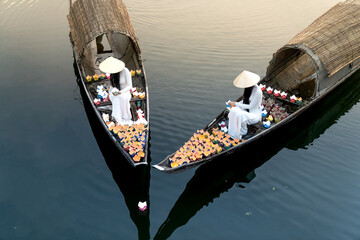 Vietnamese girls with white ao dai drop candles into the river to pray. Ao Dai is a famous traditional costume of Vietnamese women.