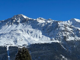 Beautiful sunlit and snow-capped alpine peaks above the Swiss tourist sports-recreational winter resorts of Valbella and Lenzerheide in the Swiss Alps - Canton of Grisons, Switzerland (Schweiz)