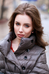 Portrait of a Young stylish brunette girl in a gray down jacket