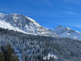 Beautiful sunlit and snow-capped alpine peaks above the Swiss tourist sports-recreational winter resorts of Valbella and Lenzerheide in the Swiss Alps - Canton of Grisons, Switzerland (Schweiz)