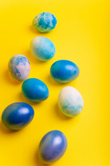 Blue dyed Easter eggs on bright yellow background from above.