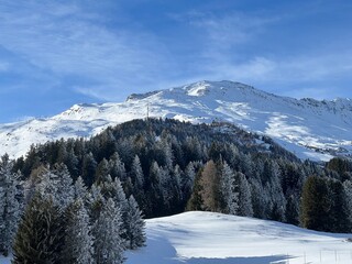 Beautiful sunlit and snow-capped alpine peaks above the Swiss tourist sports-recreational winter resorts of Valbella and Lenzerheide in the Swiss Alps - Canton of Grisons, Switzerland (Schweiz)