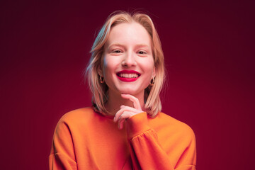 Portrait of a happy woman posing in studio and smiling at the camera isolated on magenta...