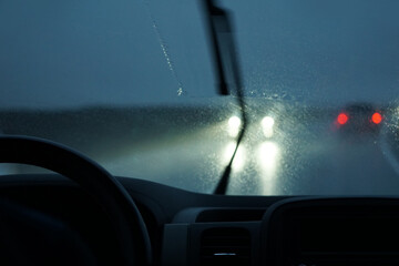 Driving a car in the rain with activated windshield wipers - obrazy, fototapety, plakaty