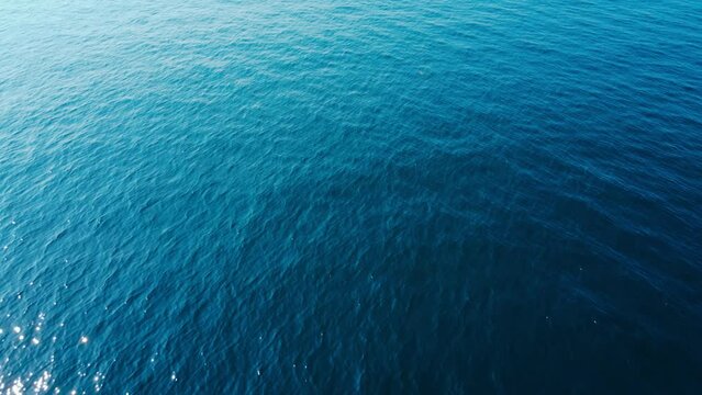 Aerial top down view of sea surface with deep blue water, moving forward