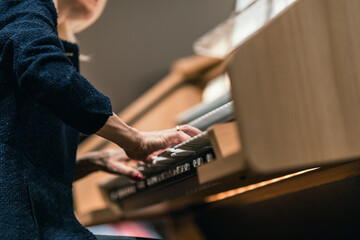 A musician playing a digital organ with three manuals