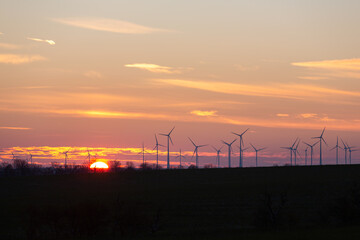Wind turbines generate energy power electricity during the evening. Sunset, Silhouettes, wind turbines, clean energy