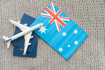 Flag of Australia with passport and toy airplane on wooden background. Flight travel concept.