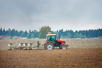 Tractor cultivating field. Tractor plowing soil on farm field. Tractor harrow plowing soil, rural landscape background. Soil cultivation, farm life. Сountryside landscape.