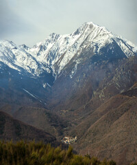Fototapeta premium Valmanya niché au pied du Barbat dans le massif du Canigou enneigé, small mountain catalan village 