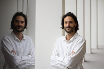 portrait d'un jeune homme de 30 ans souriant qui regarde la caméra. Il est debout dans son bureau....