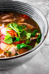 Soup Pho Bo in bowl on gray stone table
