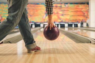 Girl throwing brown ball in bowling club, view from behind