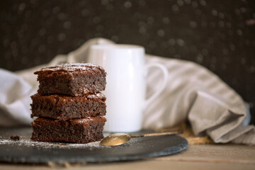 Homemade dark chocolate fudge brownies cake stacked on stone plate with copy space, dark background
