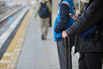 Fototapeta premium 冬の駅のホームで電車待ちの人々の姿