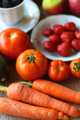 Berries in vintage porcelain dishes, other healthy fruit and vegetable on wooden table. Selective focus.