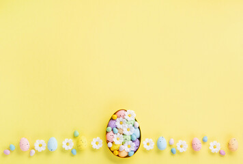 Fototapeta na wymiar Easter Eggs with Sweets and Spring Flowers on Yellow Background