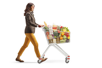 Full length profile shot of a young professional woman walking with a shopping cart