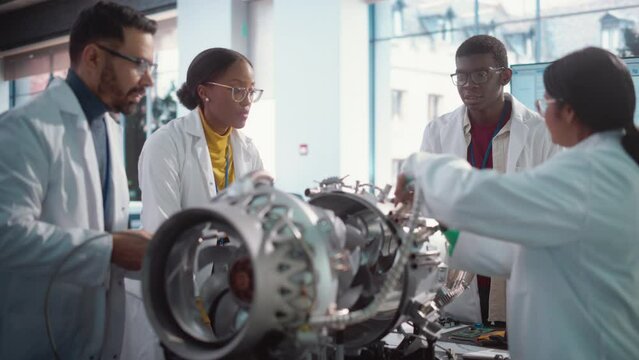 Young Black Engineer Instructing and Leading his Team, Analyzing and Researching How a Futuristic Turbofan Motor Works. Diverse Scientists Developing Innovative Technology in Industrial Facility