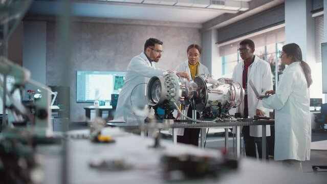 Young Female Black Engineer Leading her Team, Analyzing and Researching How a Futuristic Turbofan Motor Works. Diverse Scientists Developing Innovative Technology in Industrial High Tech Facility