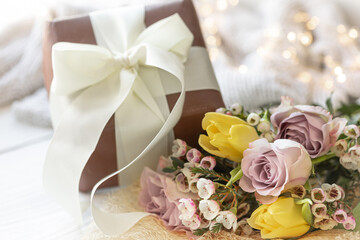 Spring composition with flowers and a gift box on a blurred background.