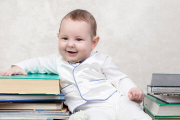 Little child among books. Happy six month old baby boy in a stack of books. The concept of early childhood education.