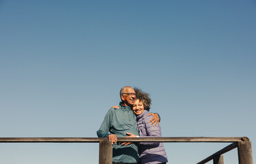 Romantic elderly couple embracing each other on a foot bridge