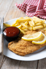 Wiener schnitzel with fried potatoes on wooden table