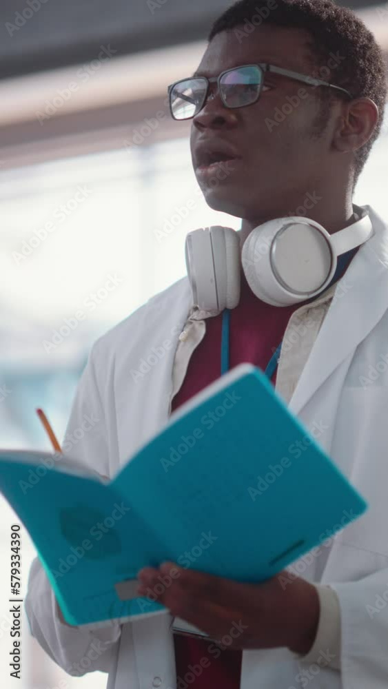 Poster vertical screen: portrait of a young black male engineering student asking questions and taking note