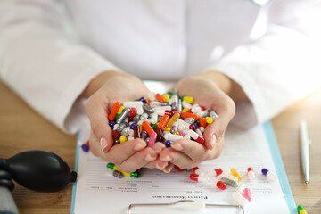 Female doctor holds bunch of different medical pills in her hands.