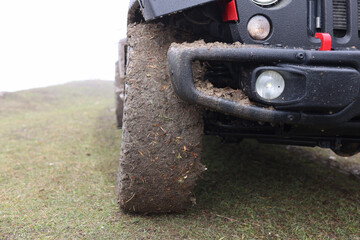 Close up of suv car with dirty wheels in field.