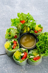 Fresh rice paper rolls with avocado, cucumber, sweet pepper, lettuce and sauce.