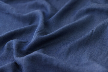 Fototapeta na wymiar Wavy blue textile as background. Blue unicolor fabric close up.