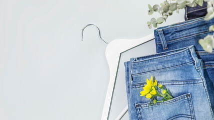 Romantic spring shopping banner with different kind of jeans with flower and white hanger on blue...
