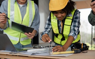 Architect team working with blueprints for architectural plan, engineer sketching a construction project on table in working site