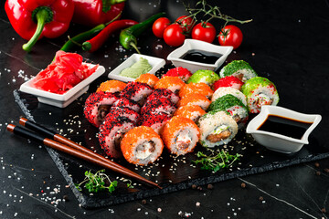Maki sushi rolls with tuna, salmon, cream cheese, flying fish caviar, greens, soy sauce, wasabi, ginger with fresh sweet pepper, cherry tomatoes.