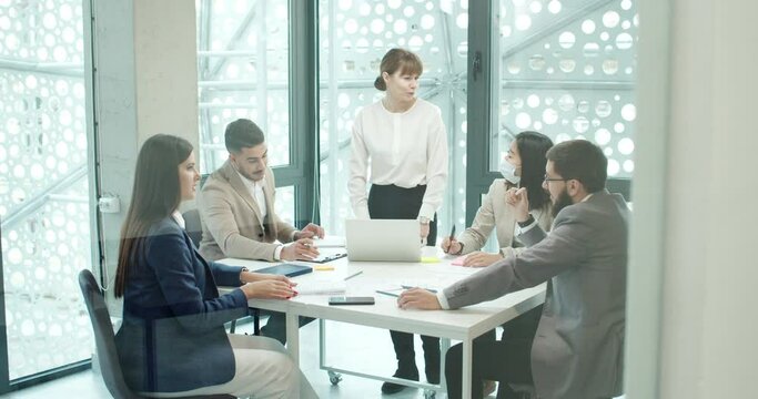 Business meeting of successful professional female project manager talking and giving tasks for productive beautiful workers of modern IT company office. Brainstorming ideas at work.